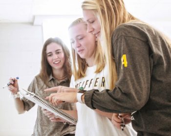 three students looking at notebook