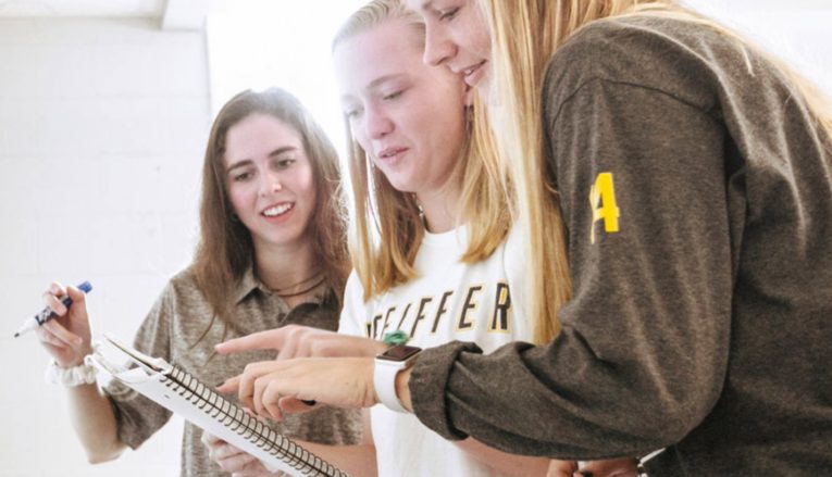 three students looking at notebook