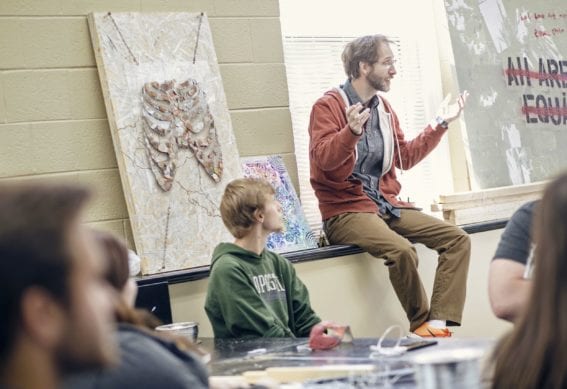 man sitting and talking to group of students