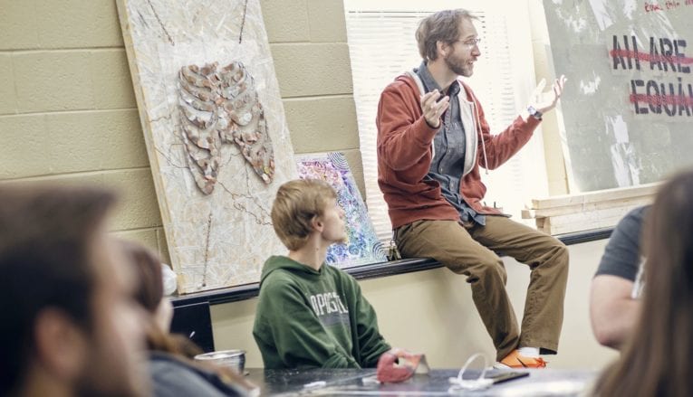 man sitting and talking to group of students