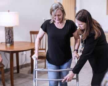 woman helping patient using walker