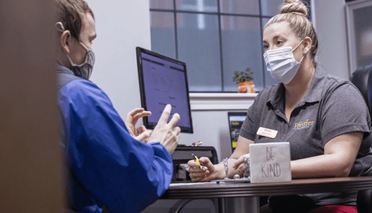 man and woman with masks talking in office