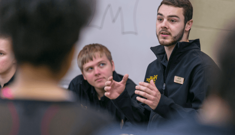 man looking at other man talking to group of people