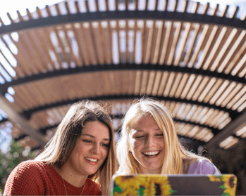 two women looking at computer, smiling and talking