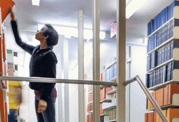 man looking at books in library