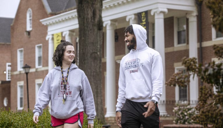 Male and female student talking and walking