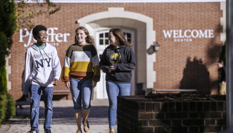 3 students walking and talking on sidewalk