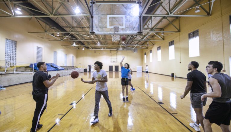 students shooting baskets in gymnasium