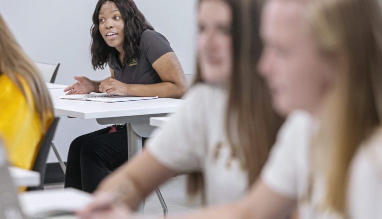 student talking in classroom at desk