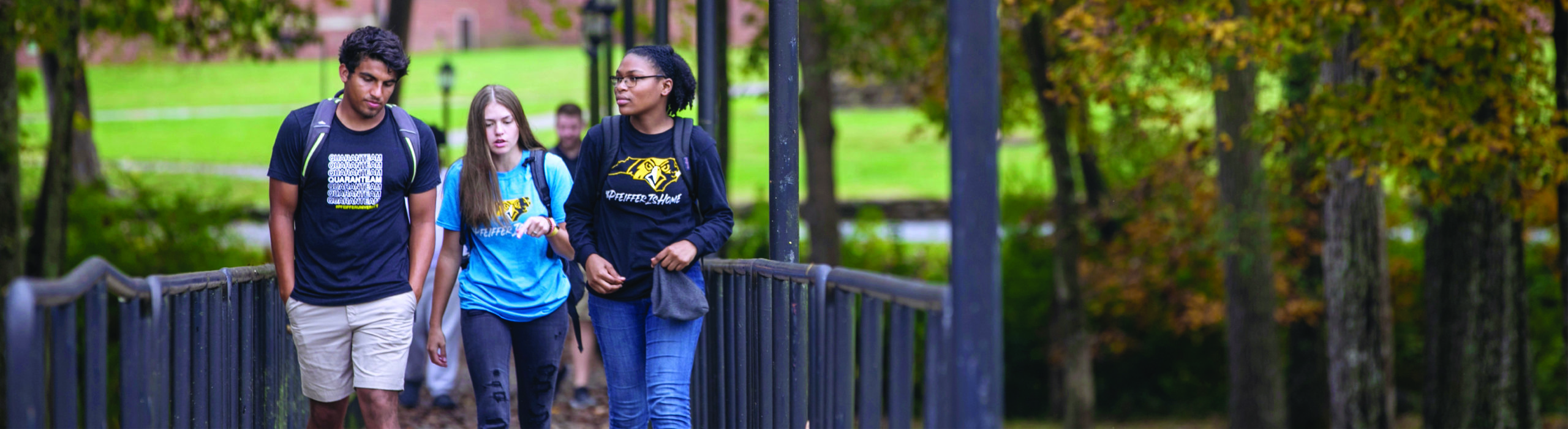 Three students walking across bridge on Pfeiffer campus