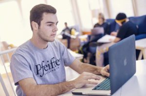 Male student working on laptop in classroom