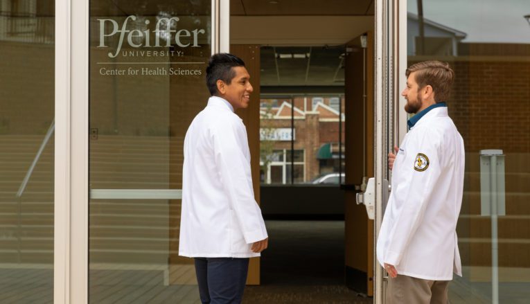 student holding door open for other student