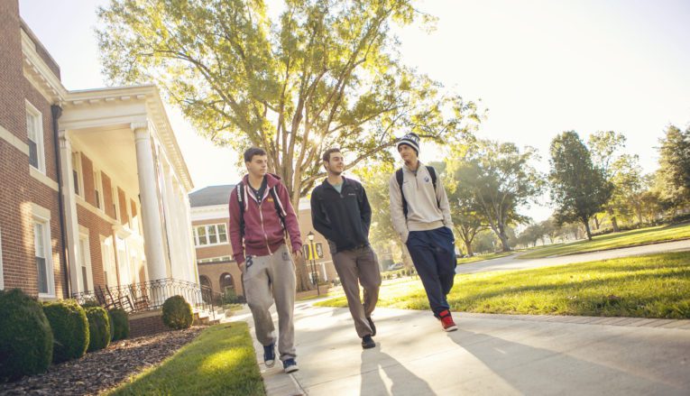 Three male students walking outside on Pfeiffer's campus