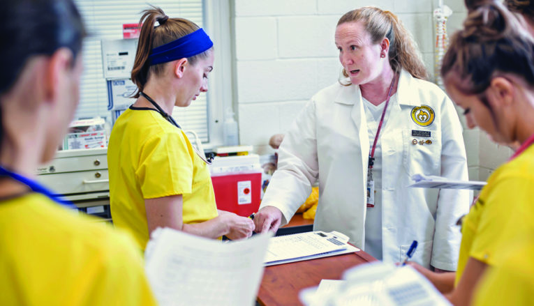 Nursing instructor and students working in lab