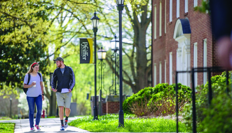 Male and female student talking and walking outside