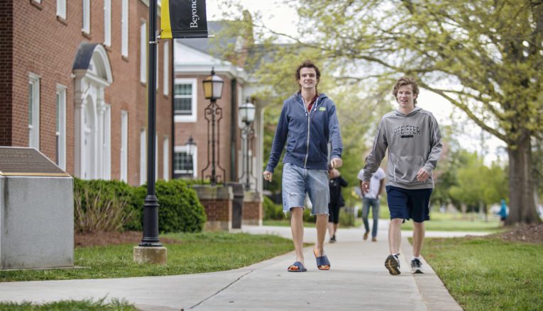 Two students walking on sidewalk