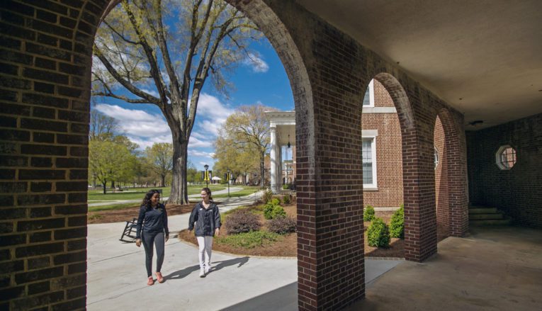 two women walking and talking on sidewalk on Pfeiffer's campus