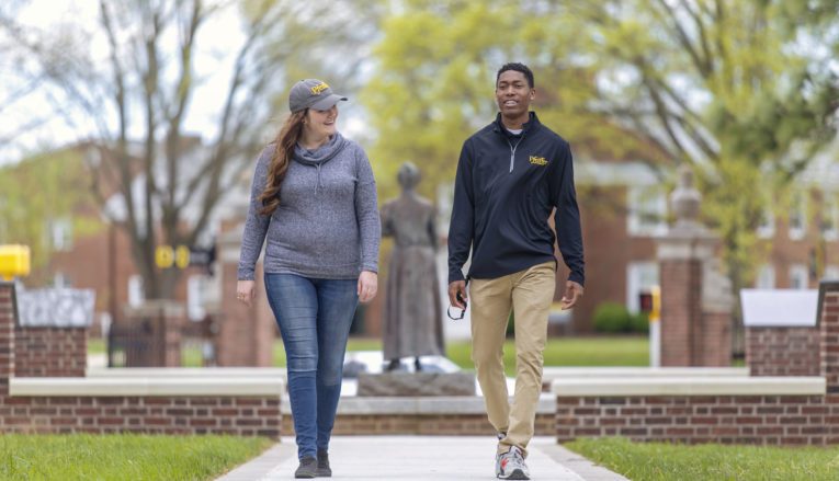 Male and female student talking and walking on Pfeiffer's campus