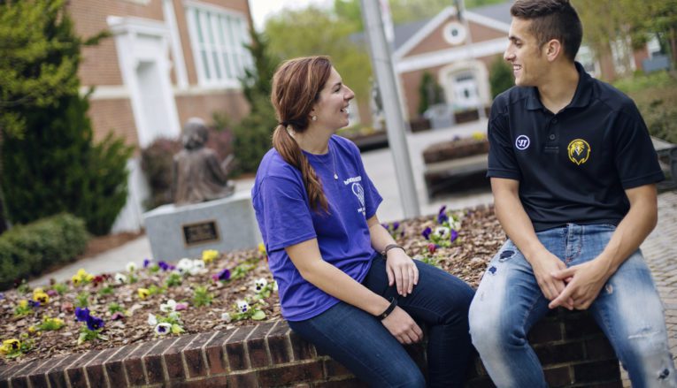 Two students outside smiling and having a conversation