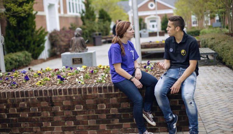 Male and female student sitting outside talking