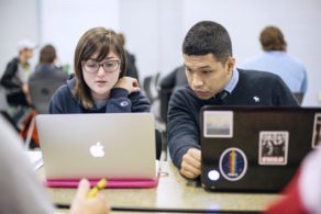two students working on laptops in class