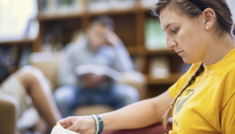 Student reading in an armchair