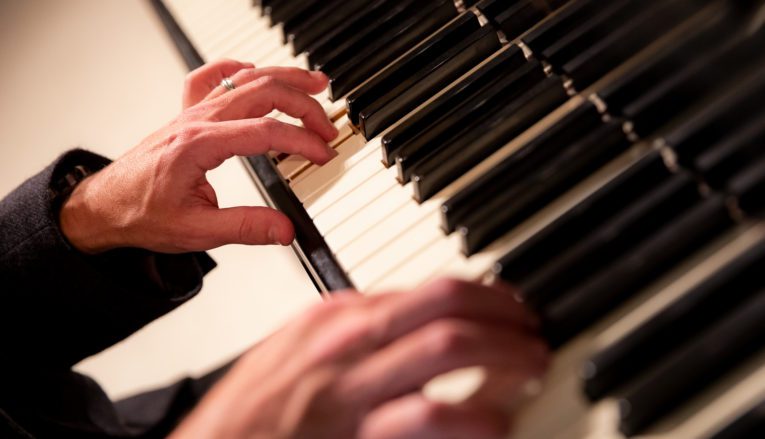 View of hands playing piano