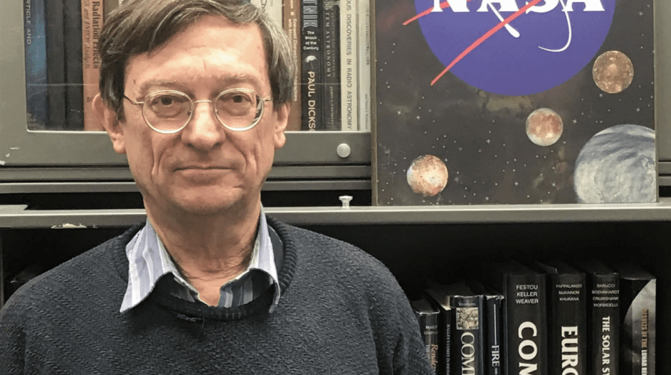 Man in front of bookshelf and NASA sign