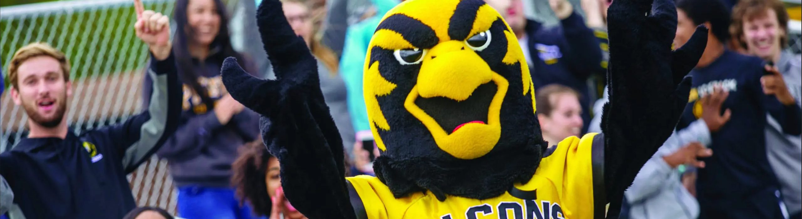 Students surrounding Pfeiffer mascot at athletic event